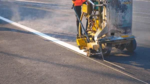 Trabajador usando maquinaria para pintar lineas en carreteras usando pintura de trafico base agua norma SCT. Quimica Altexa fabricante de pintura de tráfico base de agua y Norma SCT